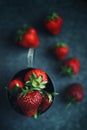 Ripe strawberries scattered around an iron mug. Dark photo