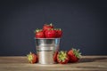 Ripe strawberries in small bucket on a wooden table against dark background.- Image Royalty Free Stock Photo