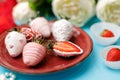 Ripe strawberries in white chocolate glaze lies on a burgundy plate on a turquoise background Royalty Free Stock Photo