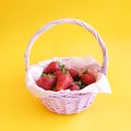 Ripe red strawberries in wicker basket on yellow background. Summer harvest. Fresh berries. Royalty Free Stock Photo