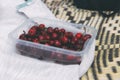 Ripe sweet cherries in a boxing box on a bedspread on the beach.