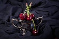 Ripe sweet cherries in small metal bowl on black fabric. Royalty Free Stock Photo