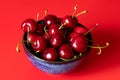 Ripe sweet cherry berries in a blue bowl on a red background Royalty Free Stock Photo