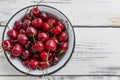 Ripe sweet cherry berries in a bowl on a light wooden background. Seasonal Vitamins. Top view. Space for text Royalty Free Stock Photo