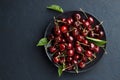 Ripe sweet cherry in black plate on dark stone background. Royalty Free Stock Photo