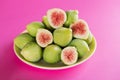 Ripe sweet green figs with green leaves. Healthy mediterranean fig fruit on a rose paper background, made in Puglia, Italy