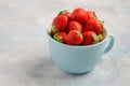 Ripe sweet strawberries in blue cup on blue concrete background. Royalty Free Stock Photo
