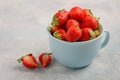 Ripe sweet strawberries in blue cup on blue concrete background. Royalty Free Stock Photo