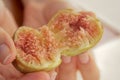 Ripe tasty figs, broken in half in female hands close up, beautiful background with a peach hue. Tropical ripe exotic fig tree Royalty Free Stock Photo