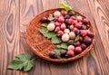 Ripe, tasty gooseberries with green leaves in a light brown crate on a wooden background. The basket full of juicy berries.