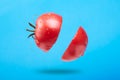 A ripe tomato cut in the air on a blue background