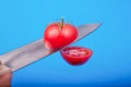 A ripe tomato cut in the air on a blue background