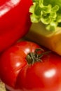 Ripe tomato and fresh green lettuce. Healthy food and vegetarianism. Close-up. Vertical Royalty Free Stock Photo