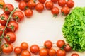 Ripe tomatoes and green lettuce on a wooden table form frame for