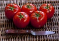 Ripe tomatoes and a knife on wicker surface Royalty Free Stock Photo