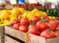 Ripe tomatoes and yellow peppers in cardboard boxes at the market, close up. On vines, blurred background of vegetables Royalty Free Stock Photo