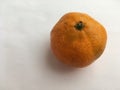 Ripe unpeeled tangerine on a white background. Minimalistic still life.