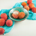 Ripe, vermilion exotic lichees decorated on a white plate kitchen table