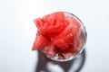 Ripe watermelon cut into pieces in a glass for whiskey on a white background