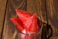 Ripe watermelon cut into pieces in a glass for whiskey on a wooden table