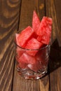 Ripe watermelon cut into pieces in a glass for whiskey on a wooden table