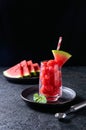 Ripe watermelon noisette balls in glass with mint on dark background. Summer dessert