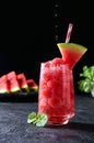 Ripe watermelon noisette balls with sada in glass and falling water drops on dark background. Refreshing summer drink