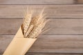 Ripe wheat ears wrapped in a bunch of kraft paper on a wooden background Royalty Free Stock Photo