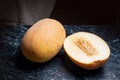 Whole and half honeydew melon fruit on dark marble background. Royalty Free Stock Photo