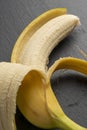 Ripe yellow banana with half peeled peels on a gray stone dark board Royalty Free Stock Photo