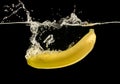 Ripe yellow banana splashing into clear water