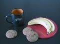 Ripe yellow bananas on a red plate, oatmeal cookies and coffee mug