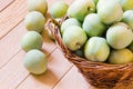 Ripe yellow-green plums in a wicker basket on a wooden table Royalty Free Stock Photo