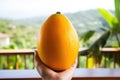 Ripe yellow mango fruit in hand against nature background. Generated by artificial intelligence