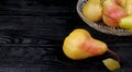 Pears in a glass plate and one pear in the foreground on wet black wooden background, place for inscription Royalty Free Stock Photo