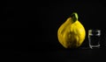 Ripe yellow quince fruit next to homemade rakia brandy glass isolated on black background.