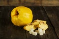 Ripe yellow quince or queen apple fruits and sliced quince lobules with seeds in craft wooden plates on black rustic wooden table Royalty Free Stock Photo