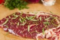 Ripened seasoned beef rump or striploin steak on wooden cut board prepared for cooking