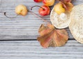 Ripening cherries and mushrooms clustered on a gray weathered picnic table with a fallen autumn leaf