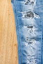 Ripped jeans on wooden background. Royalty Free Stock Photo