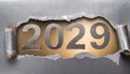 Ripped metallic paper revealling the year 2029 written in silver numbers on a golden background