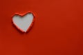 Ripped paper hole heart shaped on red paper background. Valentine`s day celebration concept Royalty Free Stock Photo