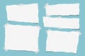 Ripped white note, notebook, copybook paper strips stuck with sticky tape on squared blue background. Royalty Free Stock Photo