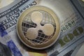 Ripple XRP golden cryptocurrency coin lying on a hundred dollars bills background.Electronic money exchange concept