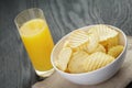 Rippled organic chips in white bowl with orange Royalty Free Stock Photo