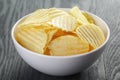 Rippled organic chips in white bowl on wooden Royalty Free Stock Photo