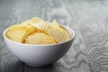 Rippled organic chips in white bowl on wooden Royalty Free Stock Photo