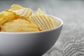 Rippled organic chips in white bowl on wooden Royalty Free Stock Photo