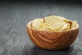 Rippled organic chips in wood bowl on wooden table Royalty Free Stock Photo