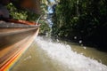 Rippled water and splashing drops behind traditional wooden long tail boat